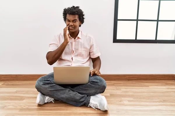 African Man Curly Hair Using Laptop Sitting Floor Touching Mouth — Stockfoto