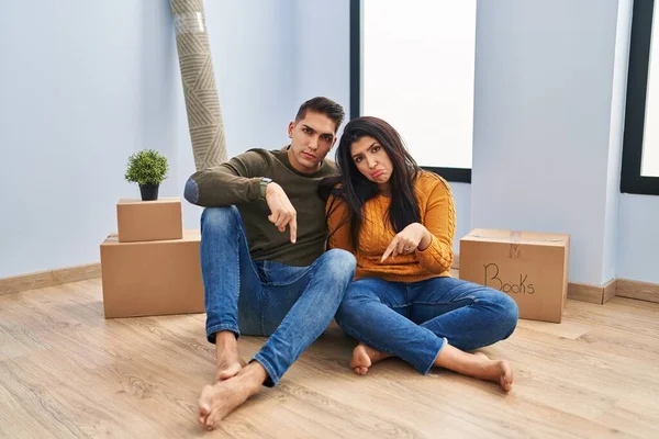 Young Couple Sitting Floor New Home Pointing Looking Sad Upset — Stock Photo, Image