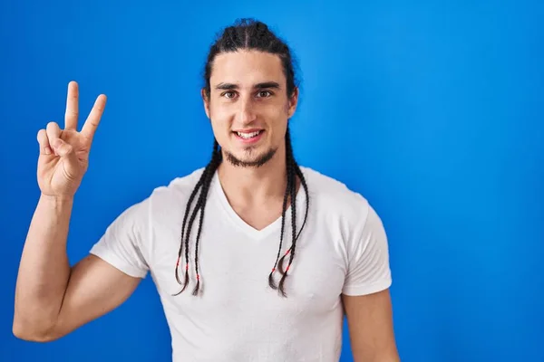 Hispanic Man Long Hair Standing Blue Background Showing Pointing Fingers — Stockfoto