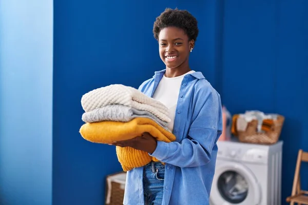 African American Woman Smiling Confident Holding Folded Clothes Laundry Room — Foto Stock