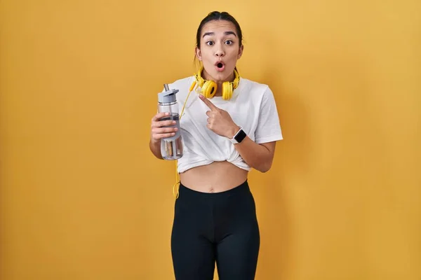 Ung Sydasiatisk Kvinna Bär Sportkläder Dricksvatten Förvånad Pekar Med Fingret — Stockfoto