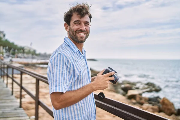 年轻的惊慌失措的男人在海滩用相机开心地笑着 — 图库照片