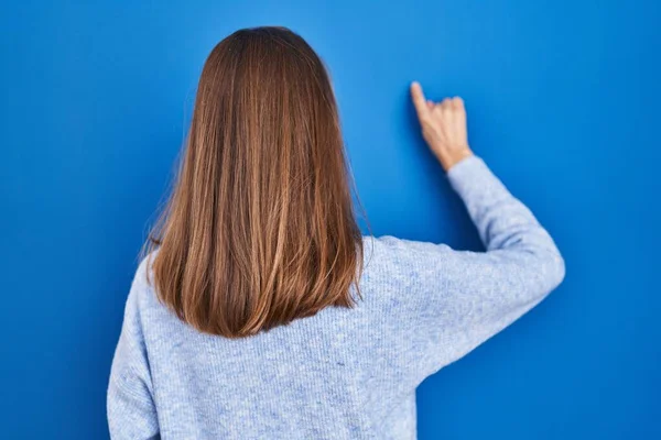 Young Woman Standing Blue Background Posing Backwards Pointing Ahead Finger — Stockfoto
