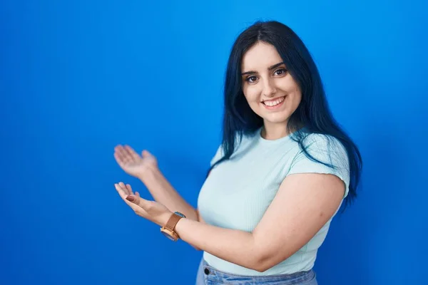 Young Modern Girl Blue Hair Standing Blue Background Inviting Enter — Φωτογραφία Αρχείου