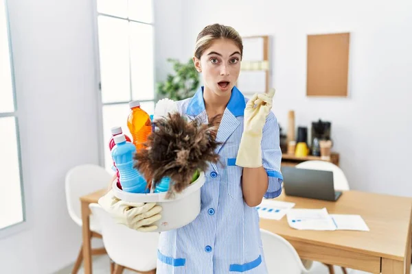 Ung Blond Kvinna Bär Renare Uniform Innehav Rengöringsmedel Förvånad Pekar — Stockfoto