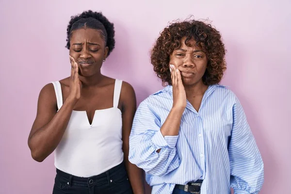 Two African Women Standing Pink Background Touching Mouth Hand Painful — Stok fotoğraf