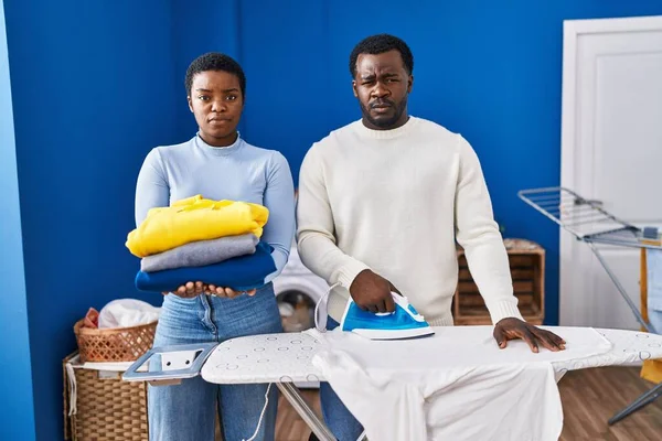 Jovem Casal Afro Americano Engomando Roupas Lavanderia Cético Nervoso Franzindo — Fotografia de Stock