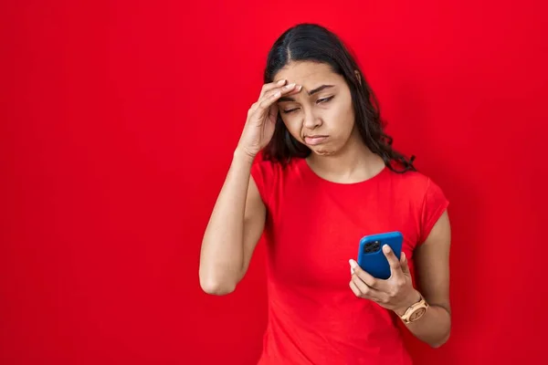 Junge Brasilianerin Mit Smartphone Über Rotem Hintergrund Besorgt Und Gestresst — Stockfoto
