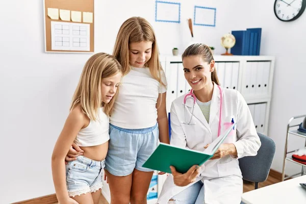 Mother and daughters doctor and patient looking book having medical session at clinic