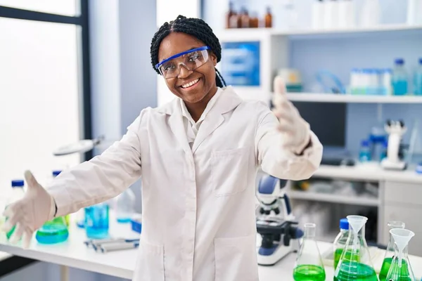 アフリカ系アメリカ人の女性が科学研究所で働いていて カメラを見て抱きしめるために開いた腕で笑っている 幸せを受け入れる陽気な表情 — ストック写真