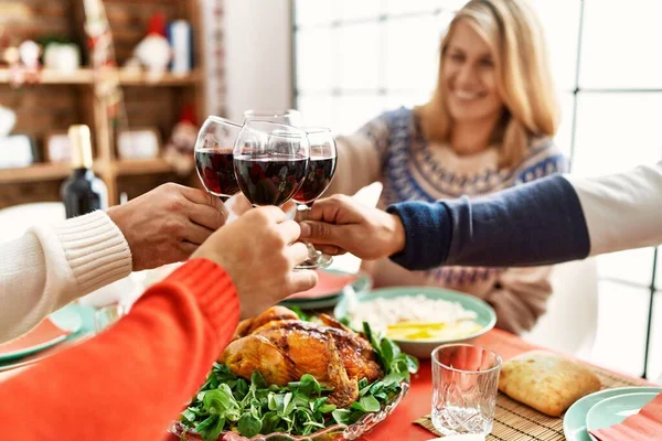 Group of middle age people smiling happy having christmas dinner toasting with wine at home.