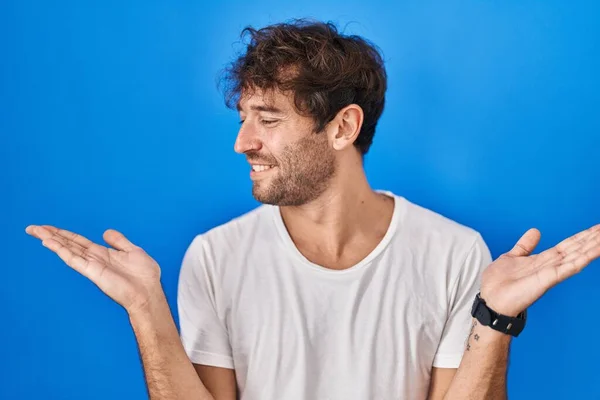 Jovem Hispânico Sobre Fundo Azul Sorrindo Mostrando Ambas Mãos Palmas — Fotografia de Stock