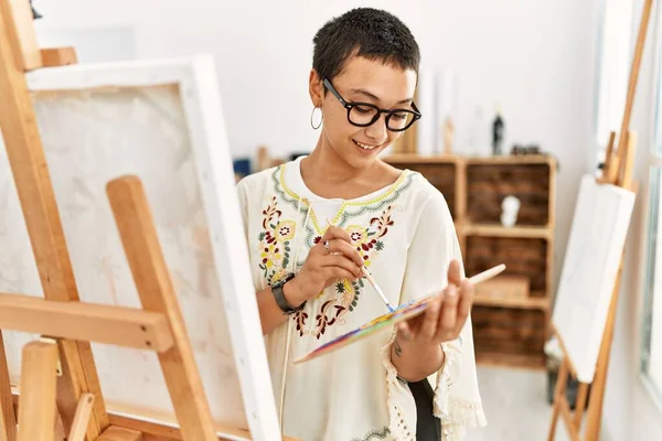 年轻的惊慌失措的女人带着自信的笑容在艺术工作室里画画 — 图库照片