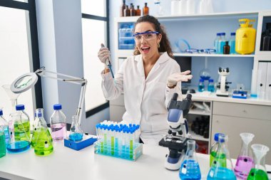 Laboratuvarda çalışan genç İspanyol kadın başarıyı mutlu bir gülümsemeyle kutluyor ve kazanan el kaldırarak ifade ediyor. 