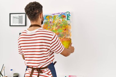 Arkaya bakan genç Arap ressam resim stüdyosunun duvarına resim çiziyor..