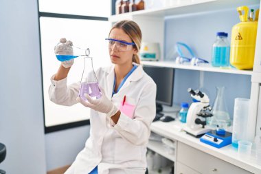 Laboratuvarda test tüpüne sıvı döken genç İspanyol bilim kadını.