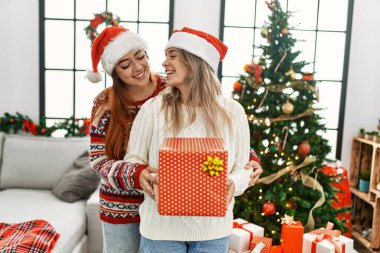 Evde Noel ağacının yanında birbirlerine sarılan bir çift.