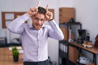 Ofisteki genç İspanyol adam komik hareketler yapıyor. Parmağını boynuz gibi kafasının üstünde gezdiriyor. 