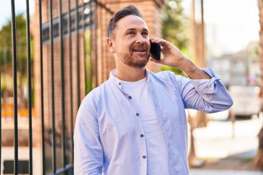 Kafkasyalı genç adam gülümsüyor. Kendine güvenen caddedeki akıllı telefondan konuşuyor.