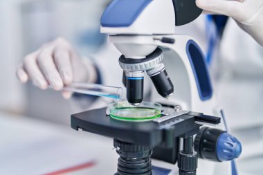 Genç İspanyol bilim adamı laboratuvarda mikroskop kullanıyor.