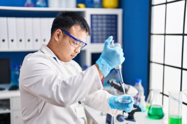 Young chinese man wearing scientist uniform working at laboratory