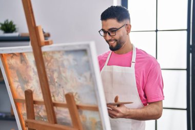 Genç Arap ressam, resim stüdyosunda kendine güvenen bir gülümseme.