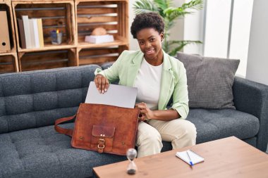 Psikoloji merkezinde çantanın dizüstü bilgisayarını tutan Afrikalı Amerikalı kadın psikolog.