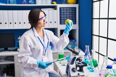 Genç ve güzel İspanyol bilim kadını. Laboratuvarda elma okuma belgesi tutuyor.