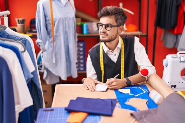 Genç İspanyol terzi atölyedeki defterde kendinden emin bir şekilde yazıyor.