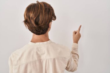 Young man standing over isolated background posing backwards pointing ahead with finger hand 