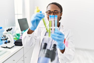 Laboratuvarda test tüpleri tutan Afrikalı Amerikalı kadın bilim adamı.