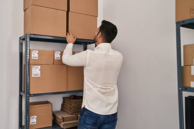 Genç İspanyol bir e-ticaret işçisi ofiste paketler düzenliyor.