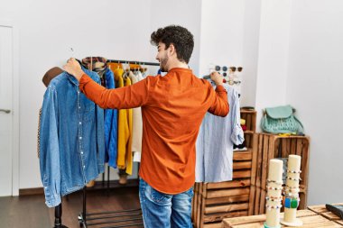 Genç İspanyol müşteri gülümsüyor. Giysi mağazasında gömlek seçerken mutlu..