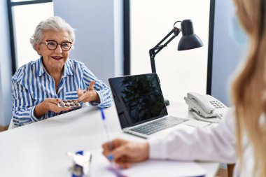 Yaşlı gri saçlı kadın klinikte tıbbi danışmanlık yapıyor.