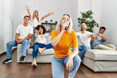 Bir grup genç arkadaş evde mikrofon kullanarak şarkı söylüyor..