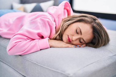 Young woman lying on sofa sleeping at home