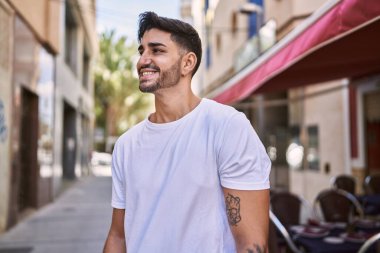 Yakışıklı İspanyol adam dışarıda mutlu gülümsüyor.