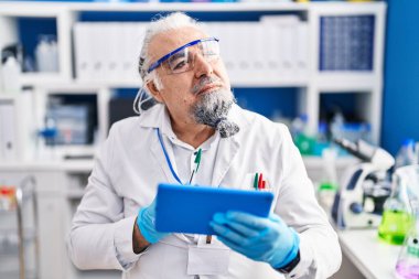 Middle age grey-haired man scientist using touchpad at laboratory
