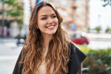 Young beautiful hispanic woman smiling confident looking to the side at street