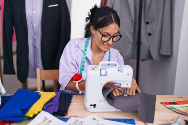 Güzel İspanyol kadın terzide dikiş makinesi kullandığından emin bir şekilde gülümsüyor.