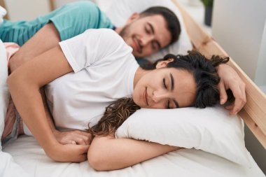 Young hispanic couple lying on bed sleeping at bedroom