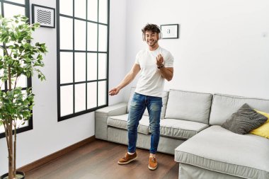 Genç İspanyol adam evde müzik dinlerken kendinden emin gülümsüyor.