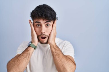 Beyaz arka plan üzerinde duran İspanyol sakallı adam korkmuş ve şok olmuş, şaşırmış ve şaşırmış bir yüz ifadesi var. 