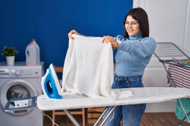 Genç ve güzel İspanyol kadın çamaşırhanede ütü yapıyor.