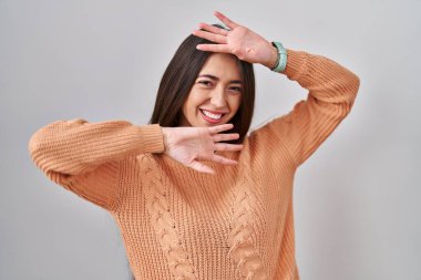 Beyaz arka planda duran esmer, neşeli gülümseyen ve elleri yüzünü gösteren genç bir kadın. Şaşırdım ve çıktım. 