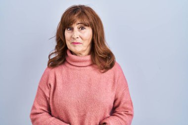 Middle age hispanic woman standing over isolated background with hands together and crossed fingers smiling relaxed and cheerful. success and optimistic 