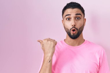 Pembe arka planda duran İspanyol genç adam elleri yana doğru işaret ederek şaşırdı, ağzı açık hayret içinde kaldı.. 