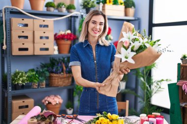 Young woman florist holding bouquet of flowers at florist