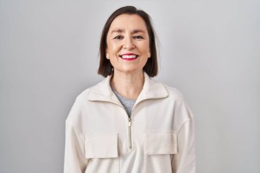 Yüzünde mutlu ve havalı bir gülümsemeyle soyutlanmış bir geçmişin başında duran orta yaşlı İspanyol kadın. şanslı kişi. 