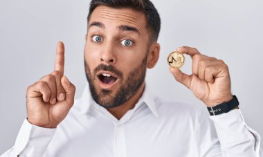 Monero kripto para tutan yakışıklı İspanyol adam bir fikir ya da soru işareti ile şaşırdı mutlu yüzle, bir numara 